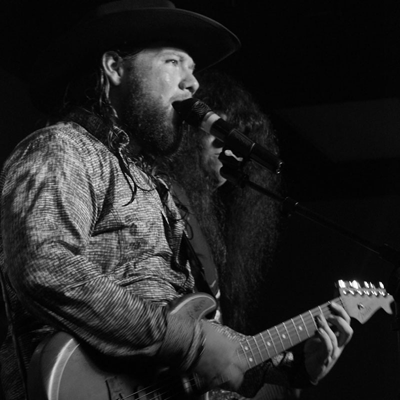 Man playing the guitar and singing on stage in Augusta, GA
